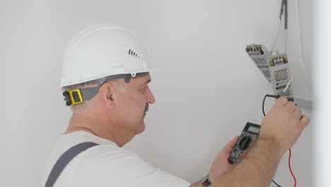 A-man-electrician-checks-the-work-of-transformers-to-illuminate-the-low-voltage-network-in-the-apartment