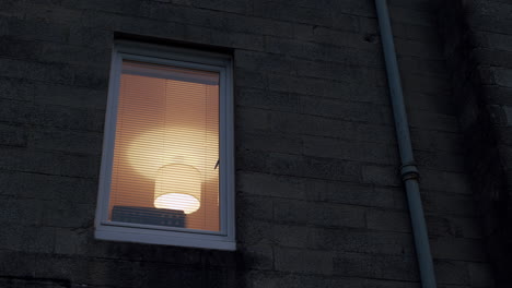 window with lamp on inside, filmed from street at night