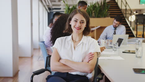 retrato de una mujer de negocios en una oficina moderna con colegas reunidos alrededor de una mesa en el fondo