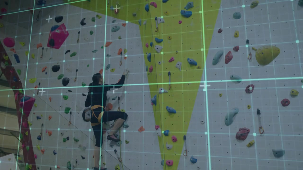 Placing left foot on lower hold, climber ascending fitness wall grabbing holds with grid lines