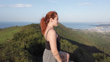 redhead woman on a mountain overlooking the sea