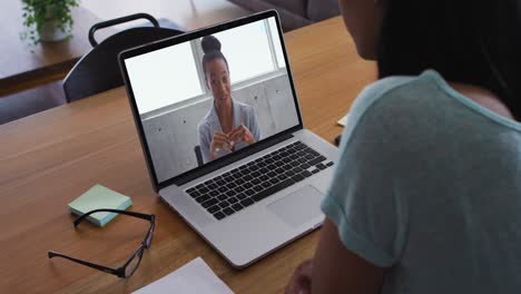 mujer afroamericana haciendo una videollamada con una colega de oficina en una computadora portátil en casa