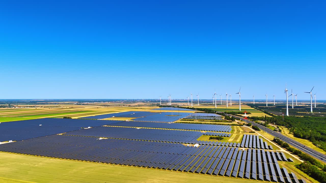 Sustainable energy is produced by the solar panels and wind farms. Aerial perspective on the fields in the countryside on sunny day
