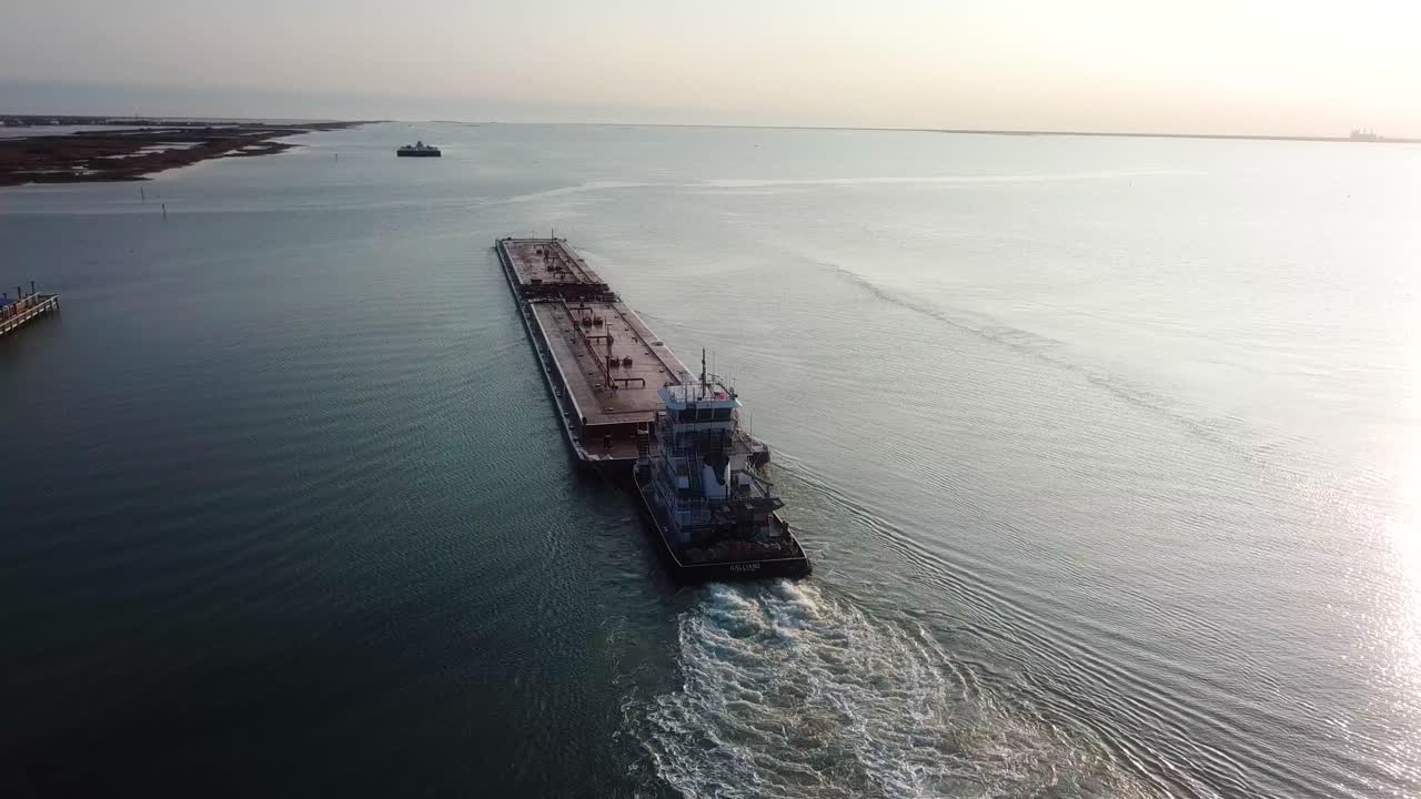 항공 보기 - 일몰 근처의 라구나 마드레(laguna madre)에 있는 걸프 연안 수로에서 또 다른 바지선을 따라가는 붉은 바지선