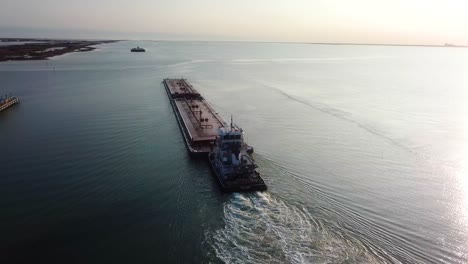 vista aérea - barcaza roja siguiendo otra barcaza en el canal intracostero del golfo en laguna madre cerca del atardecer
