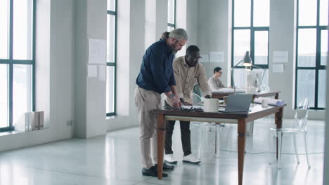 multiethnic male architects discussing project in office