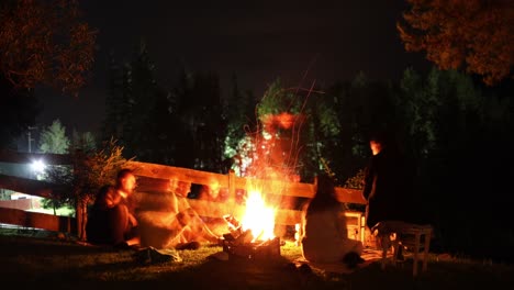 group of young people having good time together around the campfire on a hillside