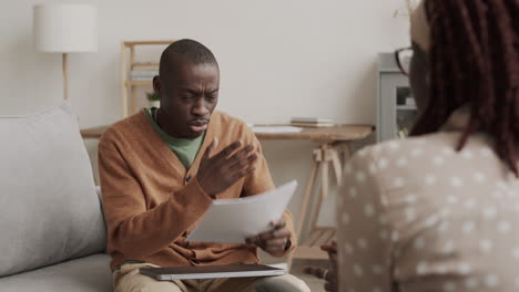 furious african man talking to woman about documents