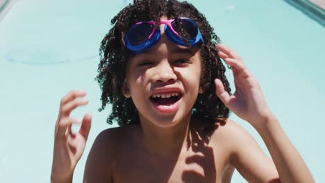 Portrait-of-happy-biracial-boy-looking-at-camera-in-swimming-pool