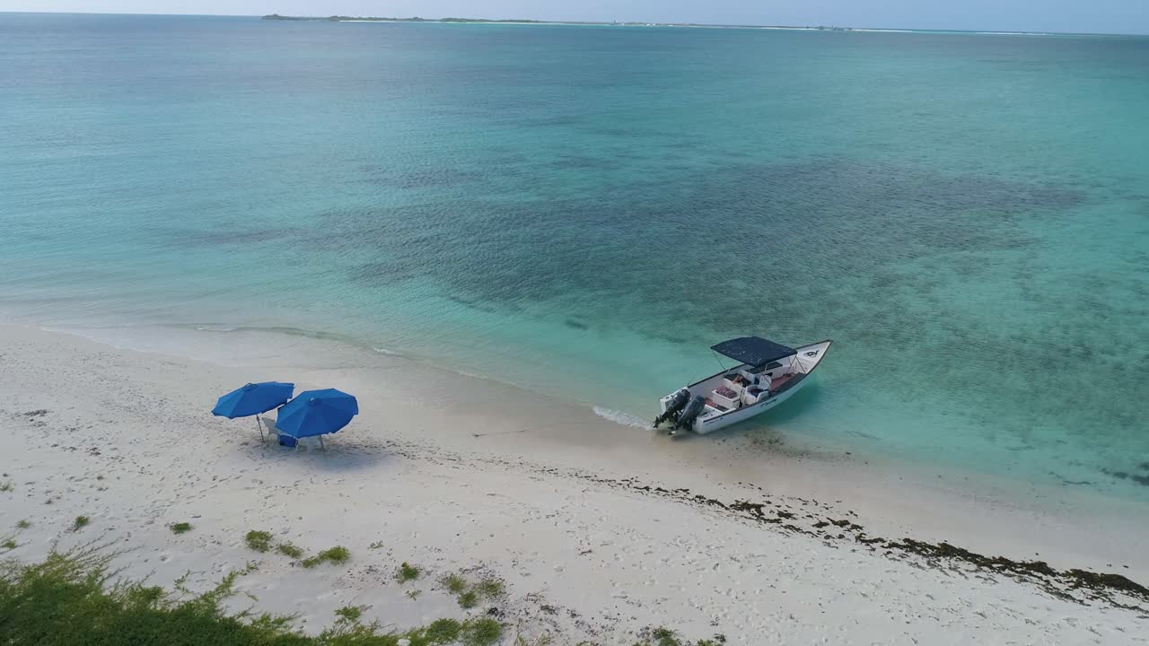 CARIBBEAN Shore white sand  beach. Motorboat and couple beach umbrellas. Vacation idyllic Island concept.