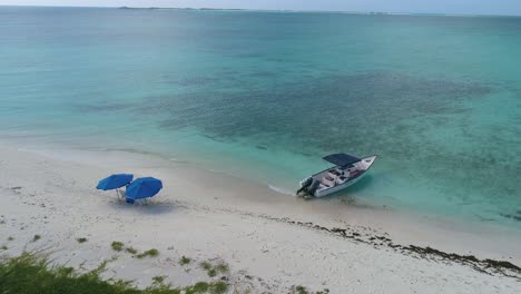 caribbean shore white sand  beach. motorboat and couple beach umbrellas. vacation idyllic island concept.