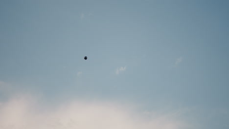 paraglider floats gracefully across wide open sky framed by wispy clouds and clear blue background, capturing sense of freedom and adventure in peaceful daytime atmosphere
