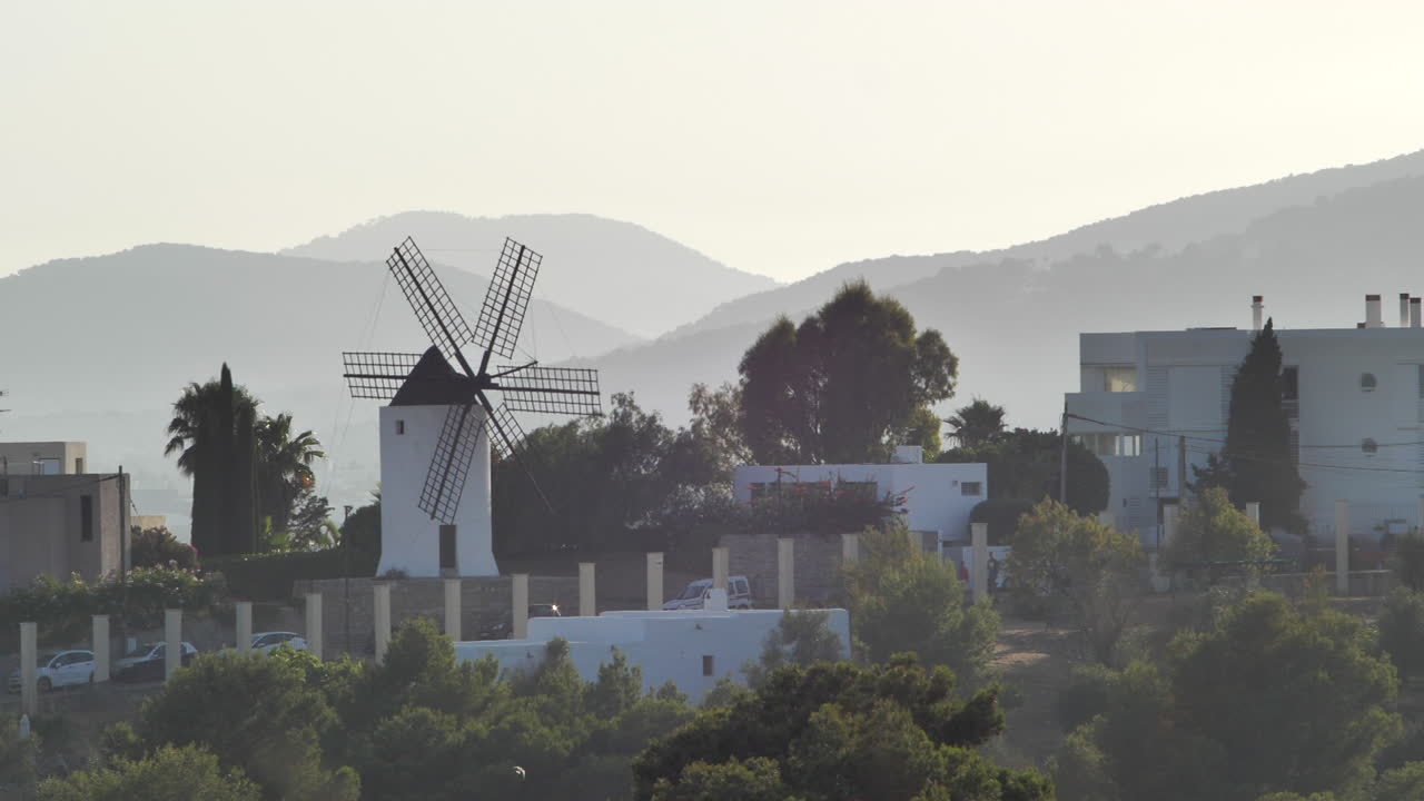 molino de viento tradicional en el paisaje de la isla de ibiza durante la puesta de sol slomo