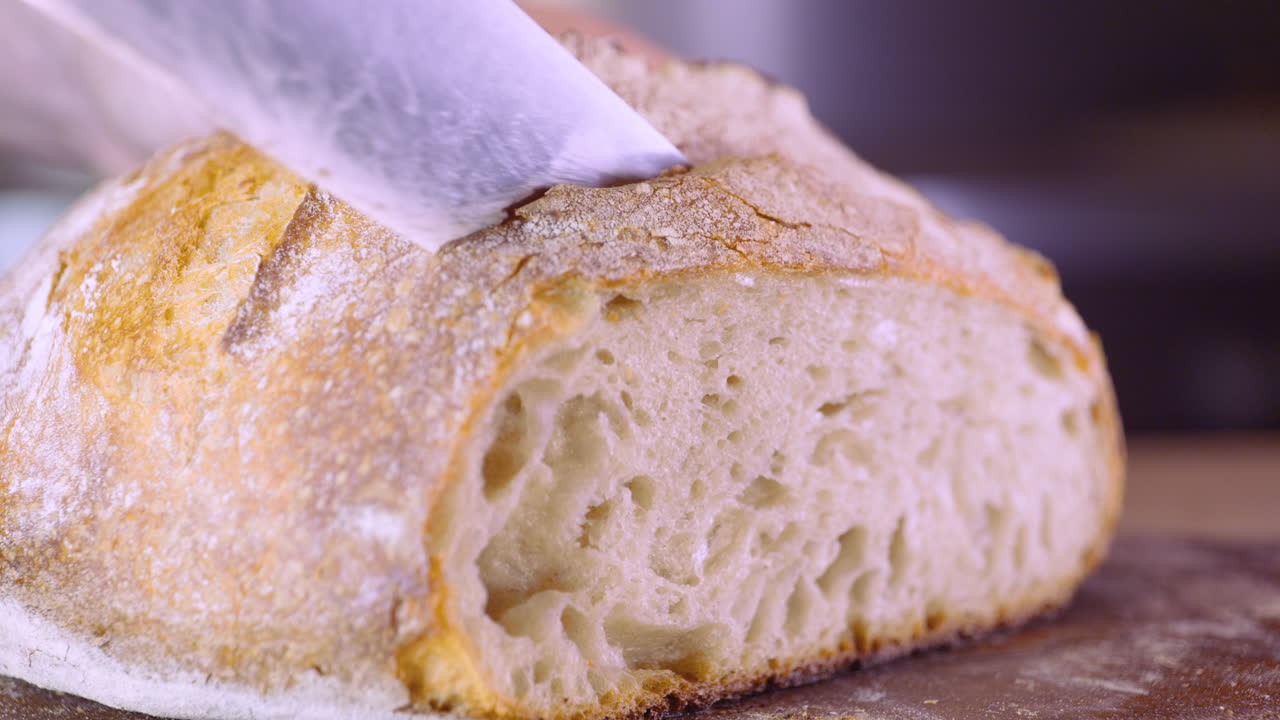 cortar pan casero de masa fermentada con cuchillo de cocina - primer plano, toma de pan