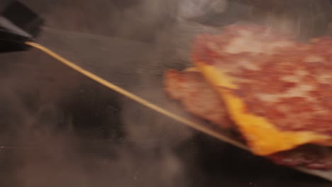 cooking american fat smash burger with cheese slice on top on grill close-up. beef or pork cutlet smashing by burger press. the chef in kitchen of the restaurant making cutlets for burgers - smash burger beefsteak. fast and street food concept.