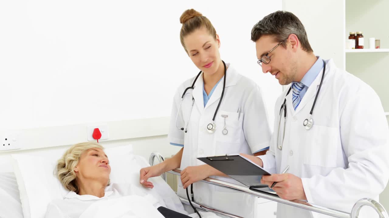 Doctors speaking with sick patient in bed