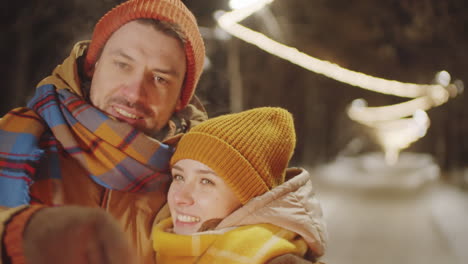 una pareja afectuosa sosteniendo bengalas navideñas y besándose al aire libre