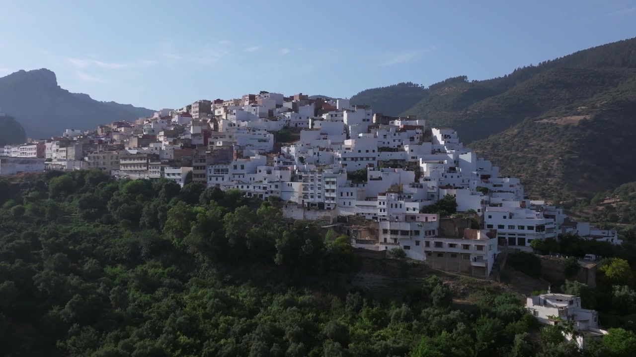 Veduta aerea cinematografica con drone di Moulay Idriss Zerhoun, Marocco, che mostra le sue iconiche case bianche in cima alla collina circondate dalle pittoresche montagne di Zerhoun.