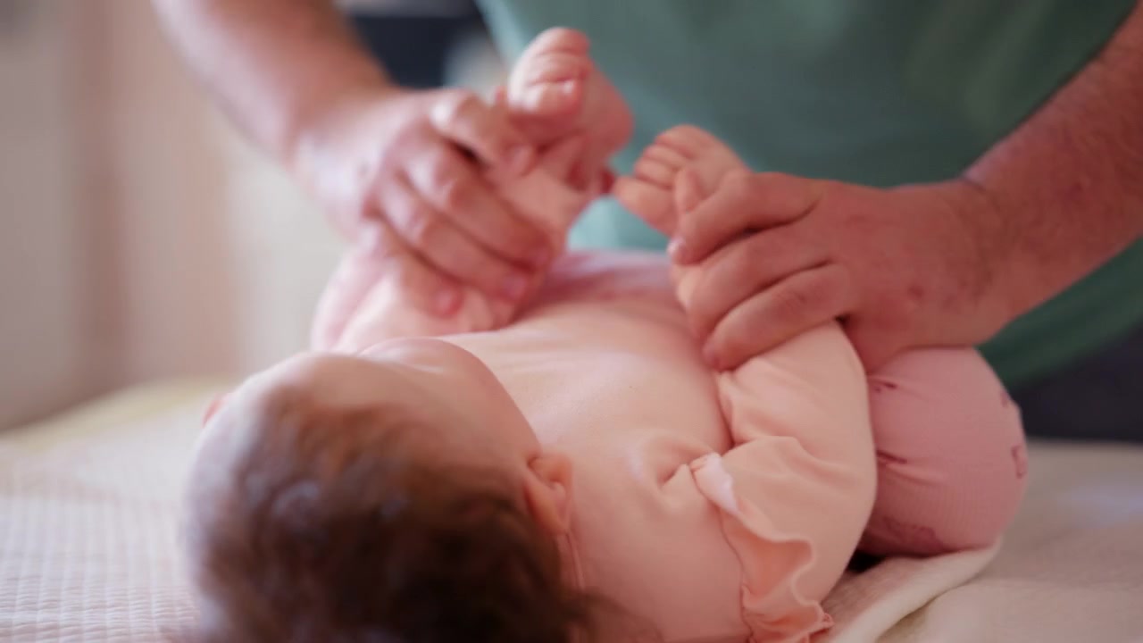 Un bambino giace comodamente mentre guarda un giocattolo colorato e fa esercizi di mobilità con un assistente.