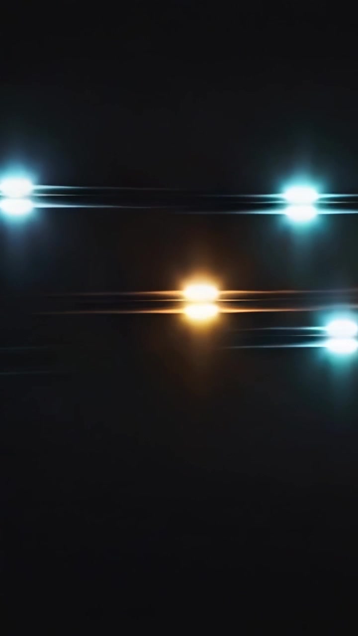 Video verticale: luce ciano che provoca spostamenti di punti colorati attraverso il vuoto nero, creando striature