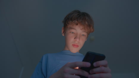 niño adolescente usando el teléfono inteligente por la noche