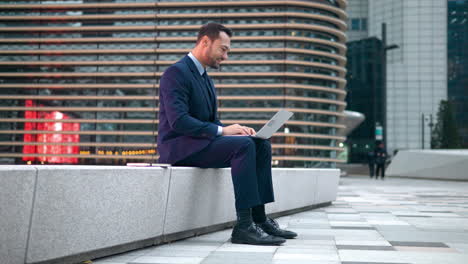 business man makes laptop video call, remote work outside office building