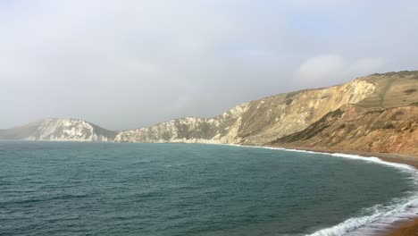 Panning-across-the-coast-of-Dorset-with-chalk-cliffs-and-the-ocean,-England