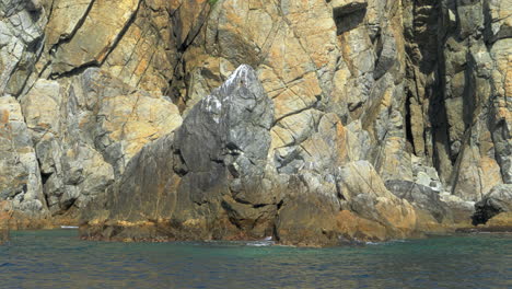 a boat passes a rock where birds roost in primorye bay