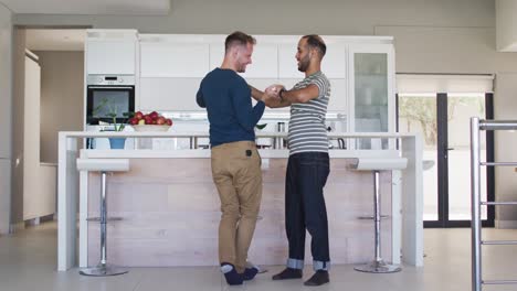 multi ethnic gay male couple dancing in kitchen