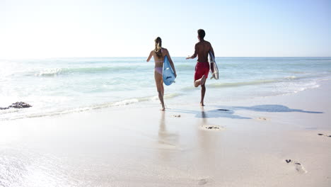 Junge-Kaukasische-Frau-Und-Gemischtrassiger-Mann-Laufen-Am-Strand-Entlang-Und-Haben-Platz-Zum-Kopieren