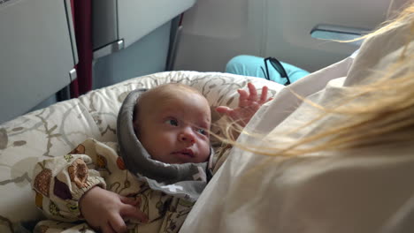 three month baby girl smiling and looking at mother during the flight