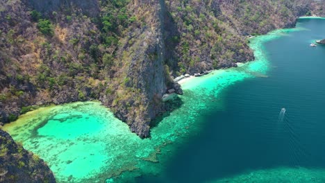 static aerial view of boat sailing by scenic coast of coron tropical island, palawan, philippines