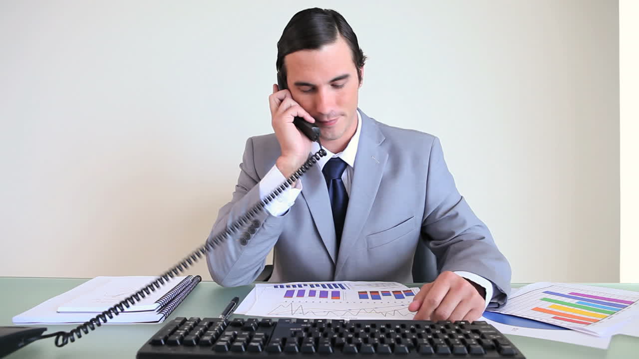 Uomo d'affari che lavora mentre risponde al telefono.