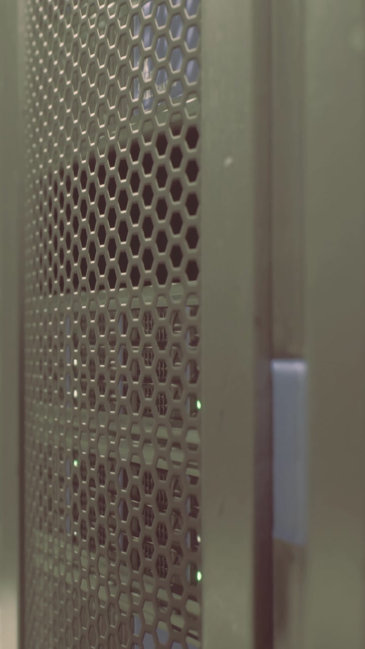 Primo piano di un server in un data center con luci verdi e griglia metallica.