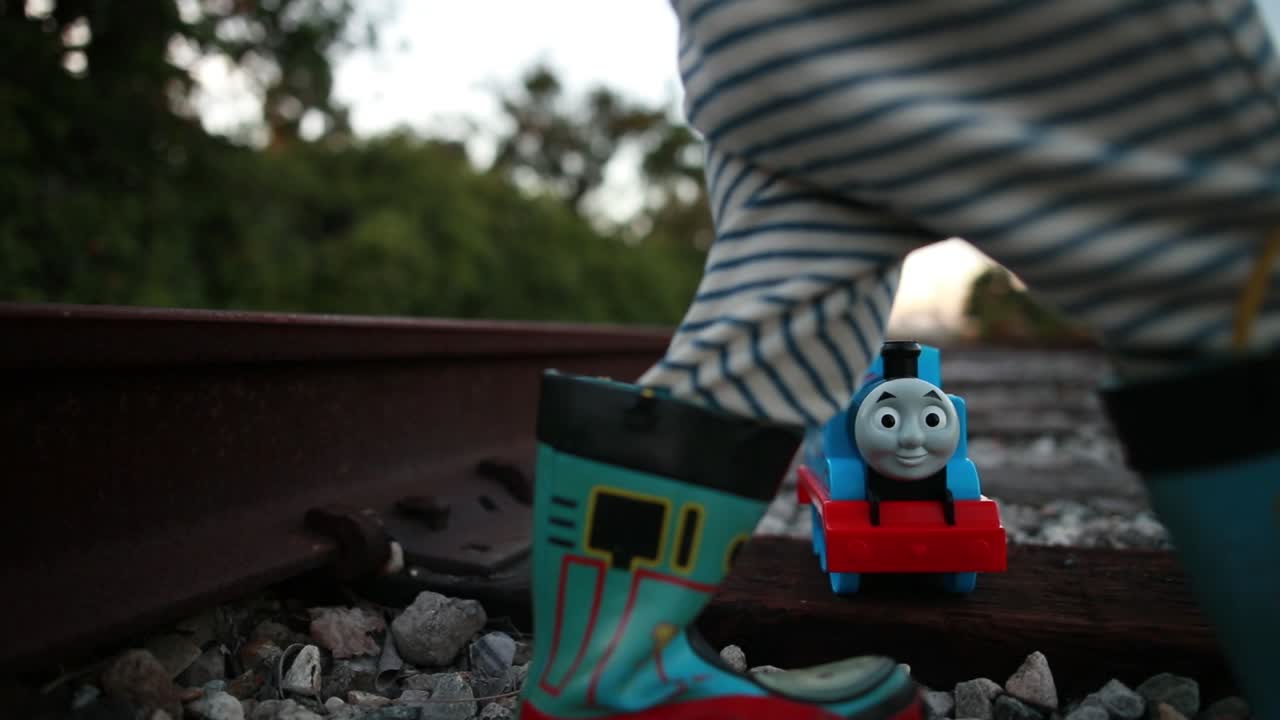 A young child has a great time playing on the train tracks pretending to be an engineer