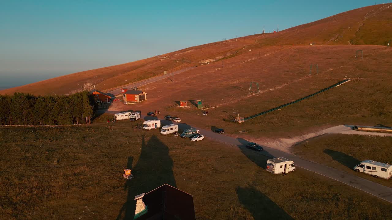 일출 동안 여름 아침 스키 리프트 근처 마젤라 산에 주차된 캠퍼밴과 밴 - 공중 풀백 드론 샷