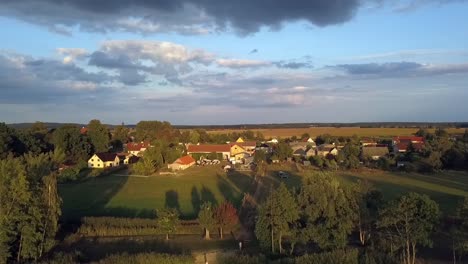 gorgeous aerial drone flight slowly rise up drone shot of a lonely blond girl in pink dress at summer sunset on a lake at small village in brandenburg germany