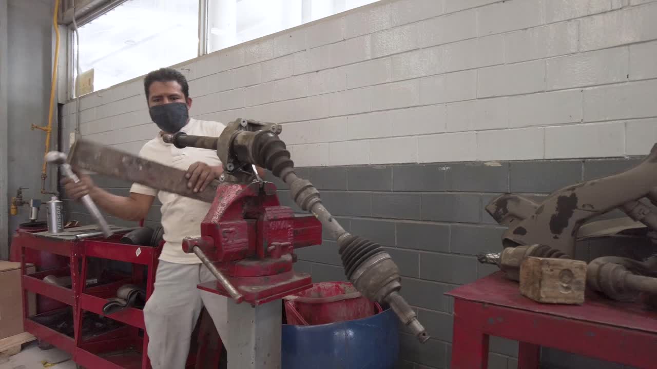 Latin male mechanic servicing the drive shaft of a car at a workshop station garage at mexico latin-america