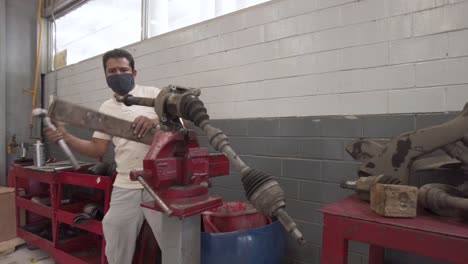 latin male mechanic servicing the drive shaft of a car at a workshop station garage at mexico latin-america