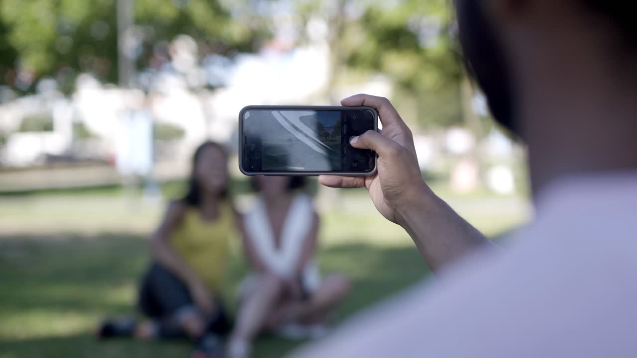 hombre fotografiando a mujeres jóvenes con un teléfono inteligente