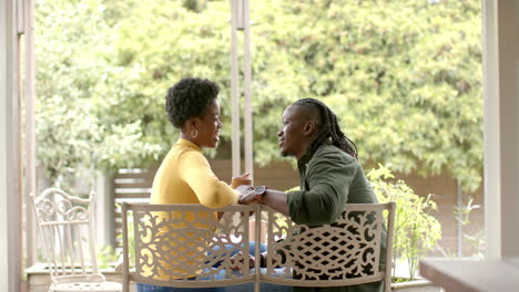 holding hands, african american couple sitting on patio, enjoying quality time together