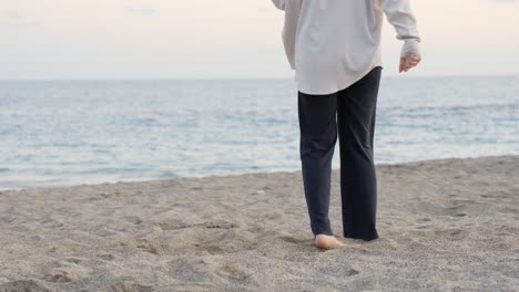 person dancing barefoot in slow motion on warm sandy beach, medium shot