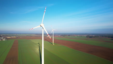 aerial view of pair of wind turbines with spinning propellers in green field
