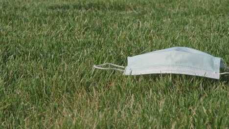 Disposable-Surgical-Facemask-Left-On-Freshly-Cut-Green-Grass-On-A-Sunny-Spring-Day