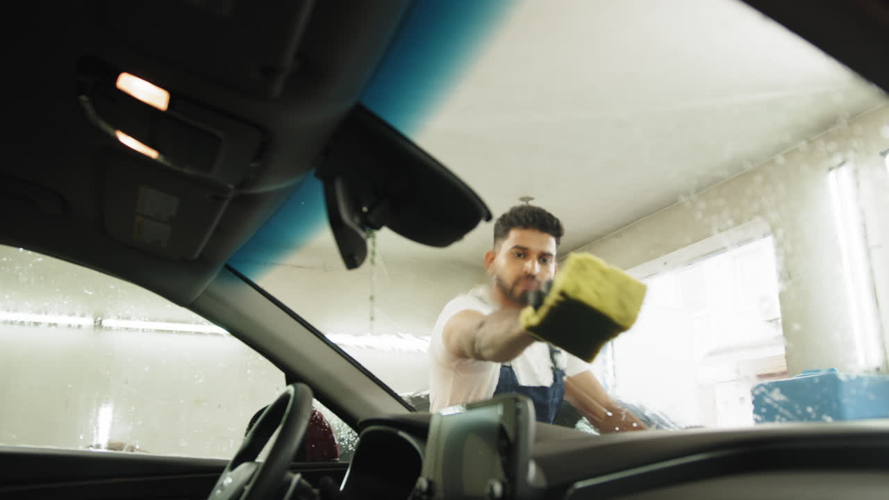 자동차 세탁소 에서 자동차 창문 을 청소 하는 사람