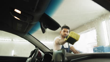hombre limpiando una ventana de coche en un lavado de coches