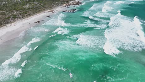 Vista-Aérea-De-Pájaro-De-Un-Kitesurf-Rozando-El-Agua-Verde-Cerca-Del-Cabo-De-Buena-Esperanza,-Sudáfrica