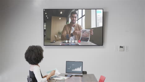 mujer de negocios afroamericana en una llamada de video con un colega afroamericano en la pantalla de televisión