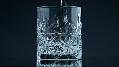 crystal water pouring glass at dark background closeup. fresh liquid splashing