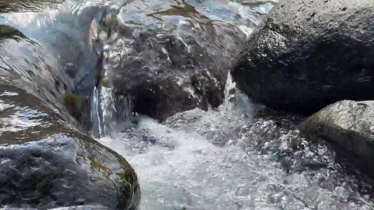 Acqua limpida che scorre sopra rocce scure del fiume